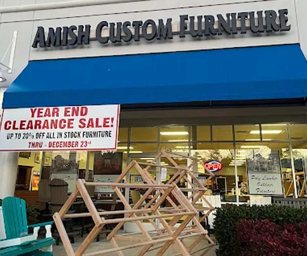 Amish furniture blog photo of Williamsburg storefront with year-end clearance sale banner and wood displays