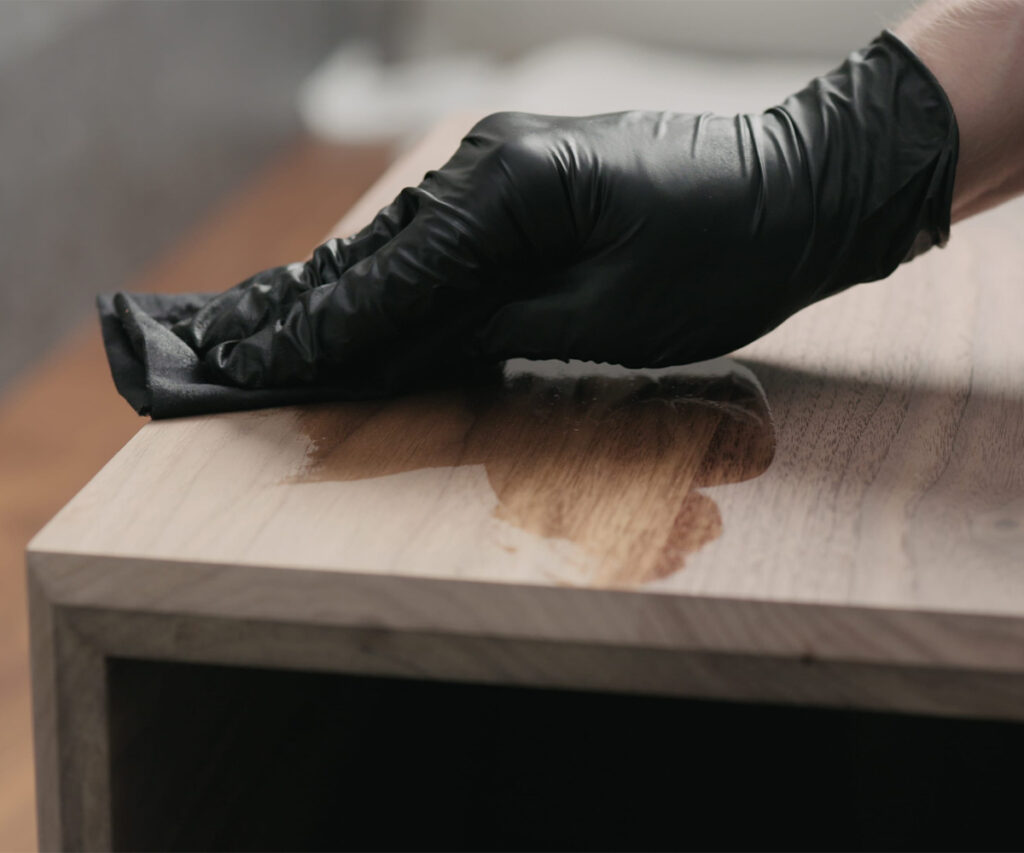 Gloved hand applying finish to a solid wood tabletop