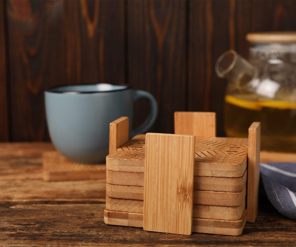 Wooden coasters beside a mug and glass bottle on a wood table
