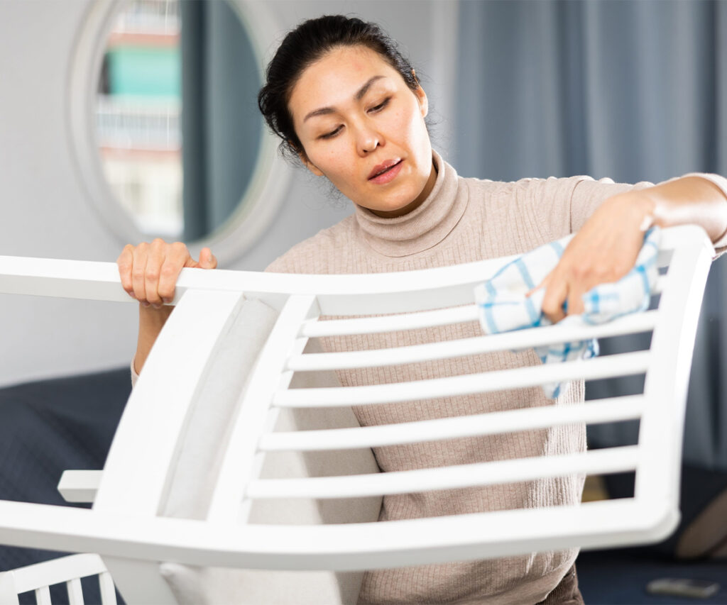 Woman cleaning painted chair slats with a soft cloth